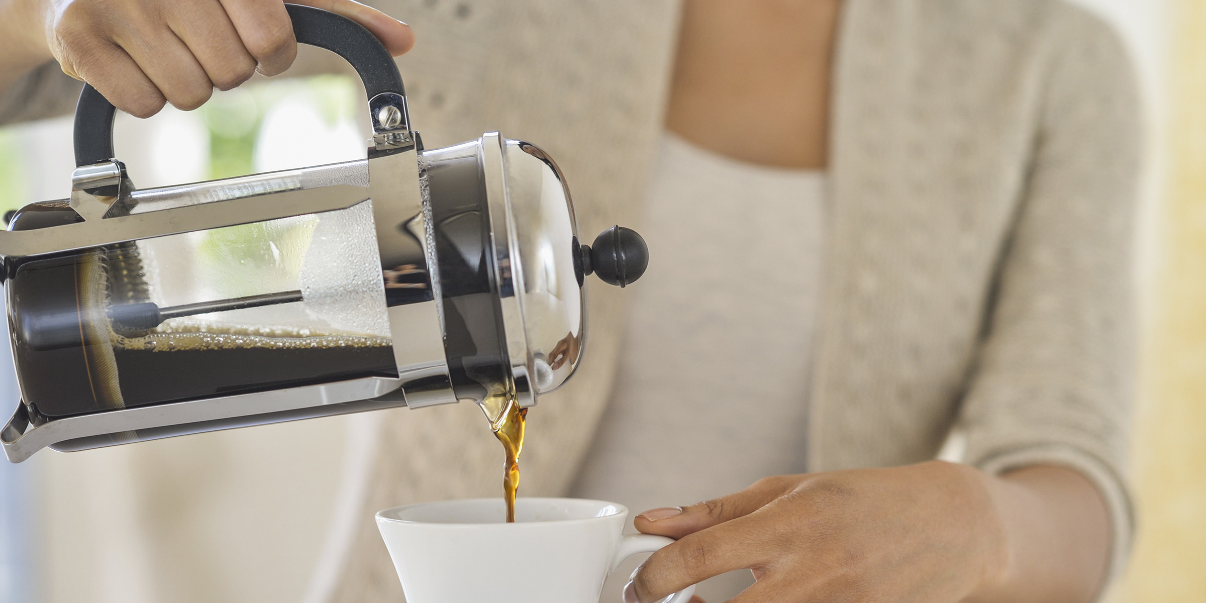 A woman pouring coffee into a cup.