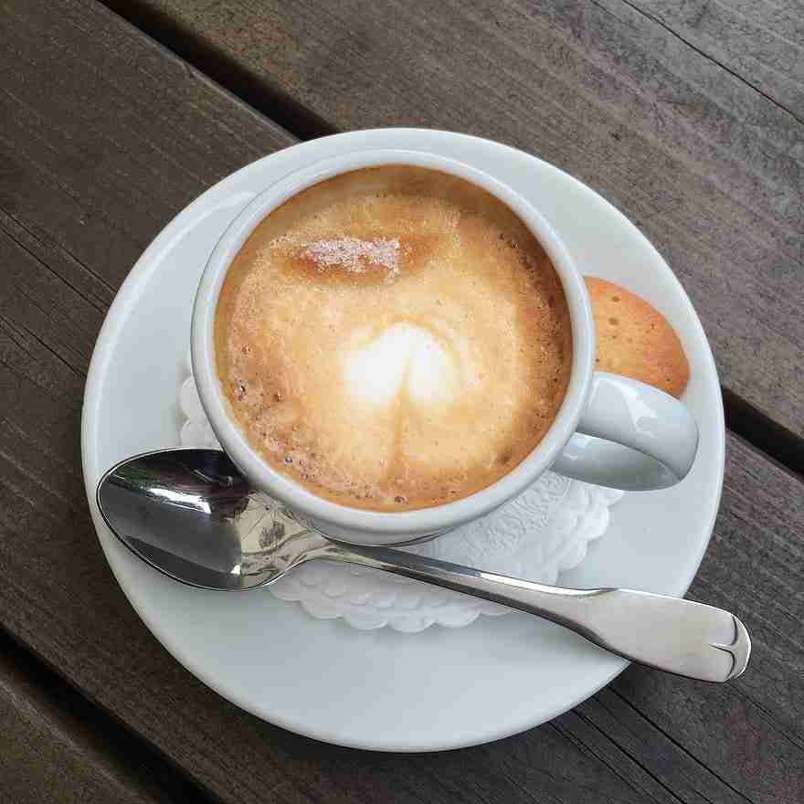 A cup of coffee with a spoon on a wooden table.