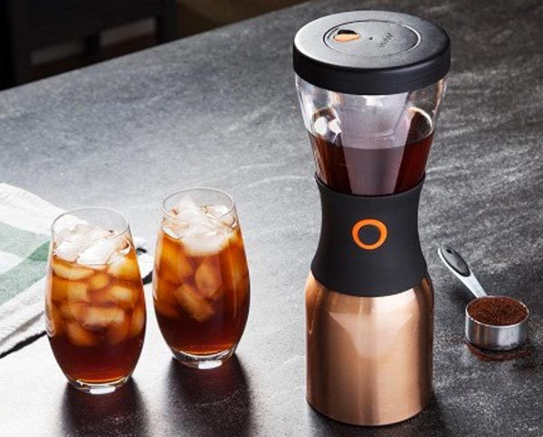 A coffee maker next to two glasses of iced coffee.