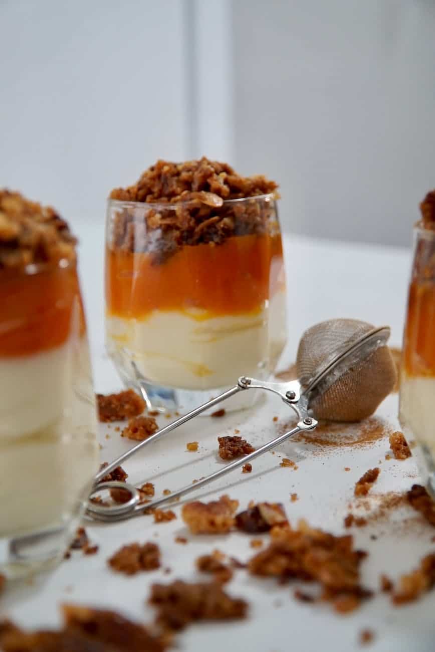 cream dessert with fruit sauce and crumble in drinking glasses