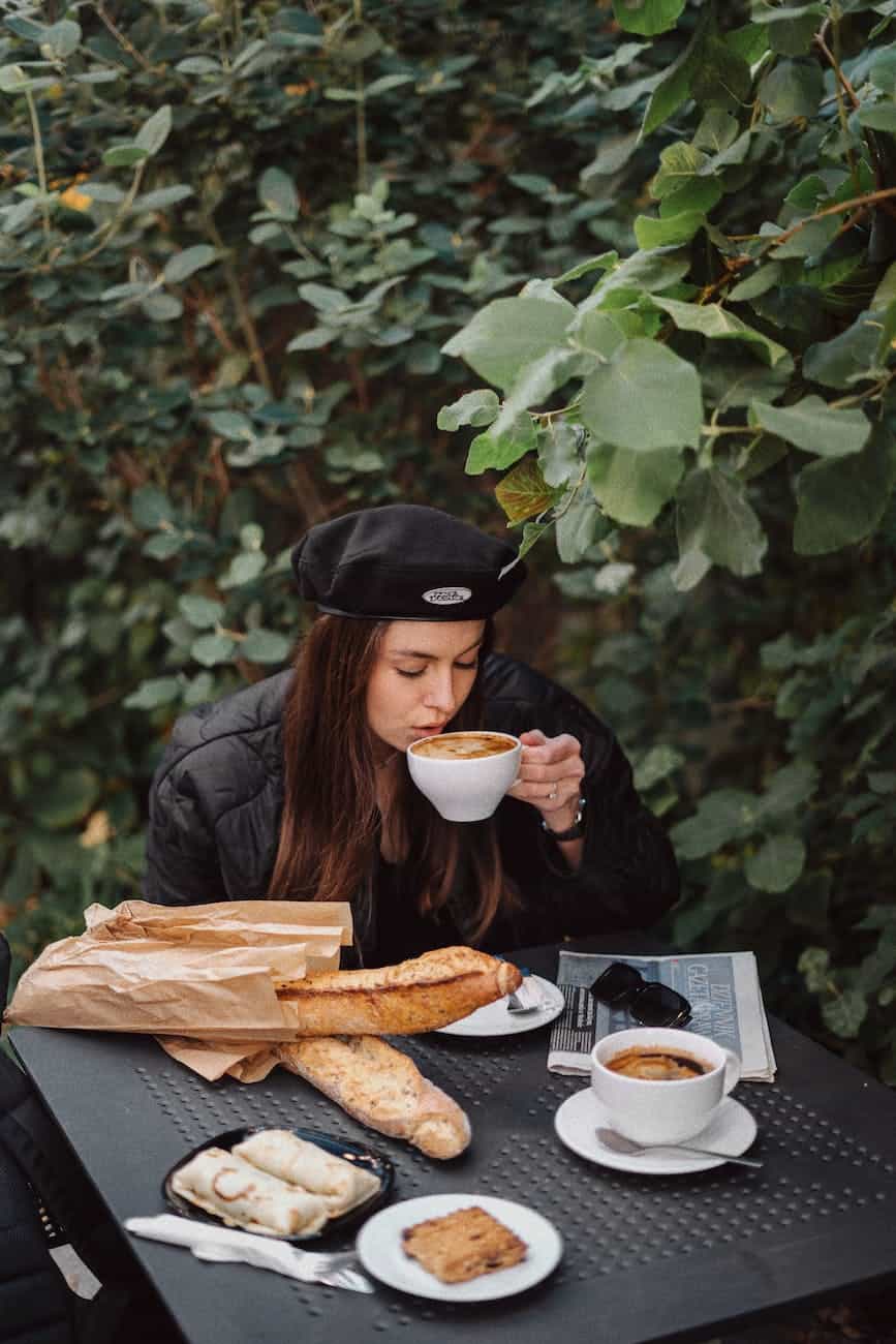 woman drinking coffee and eating french breakfast