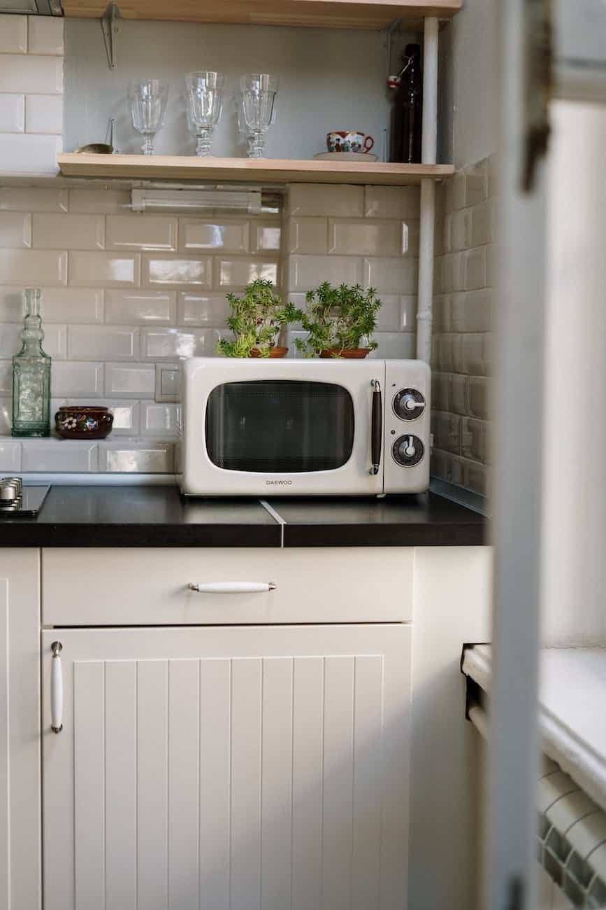 silver microwave oven on white wooden cabinet