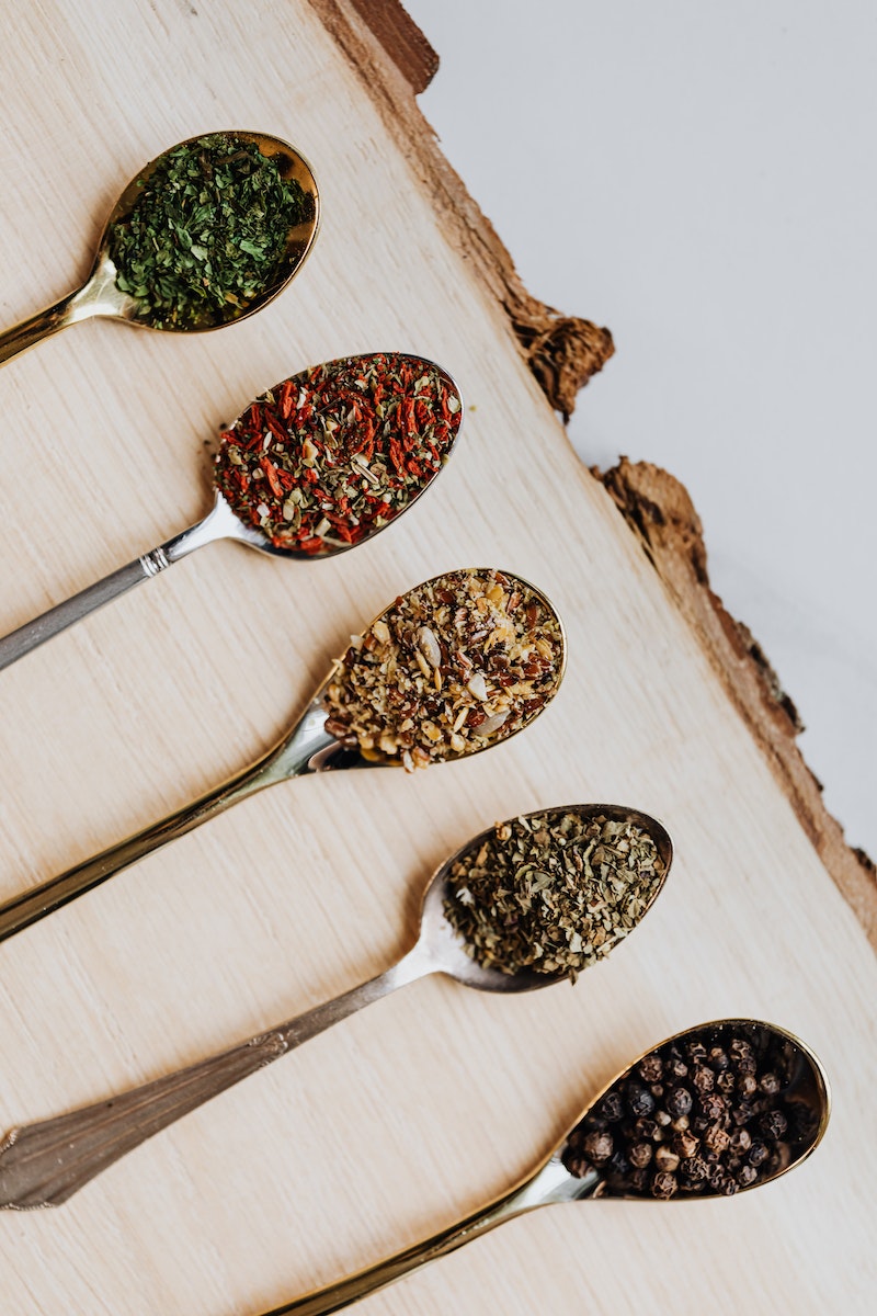 Teaspoons of Spices and Herbs on Wooden Board