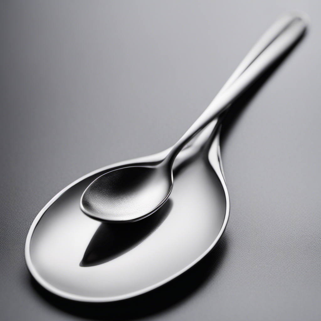 An image showcasing a sleek silver teaspoon delicately holding 16 grams of a fine white powder, gently cascading onto a surface, illustrating the precise measurement of 16g in teaspoons